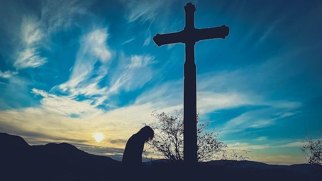 A man kneeling before a cross, showing how to accept God's forgiveness and forgive yourself.